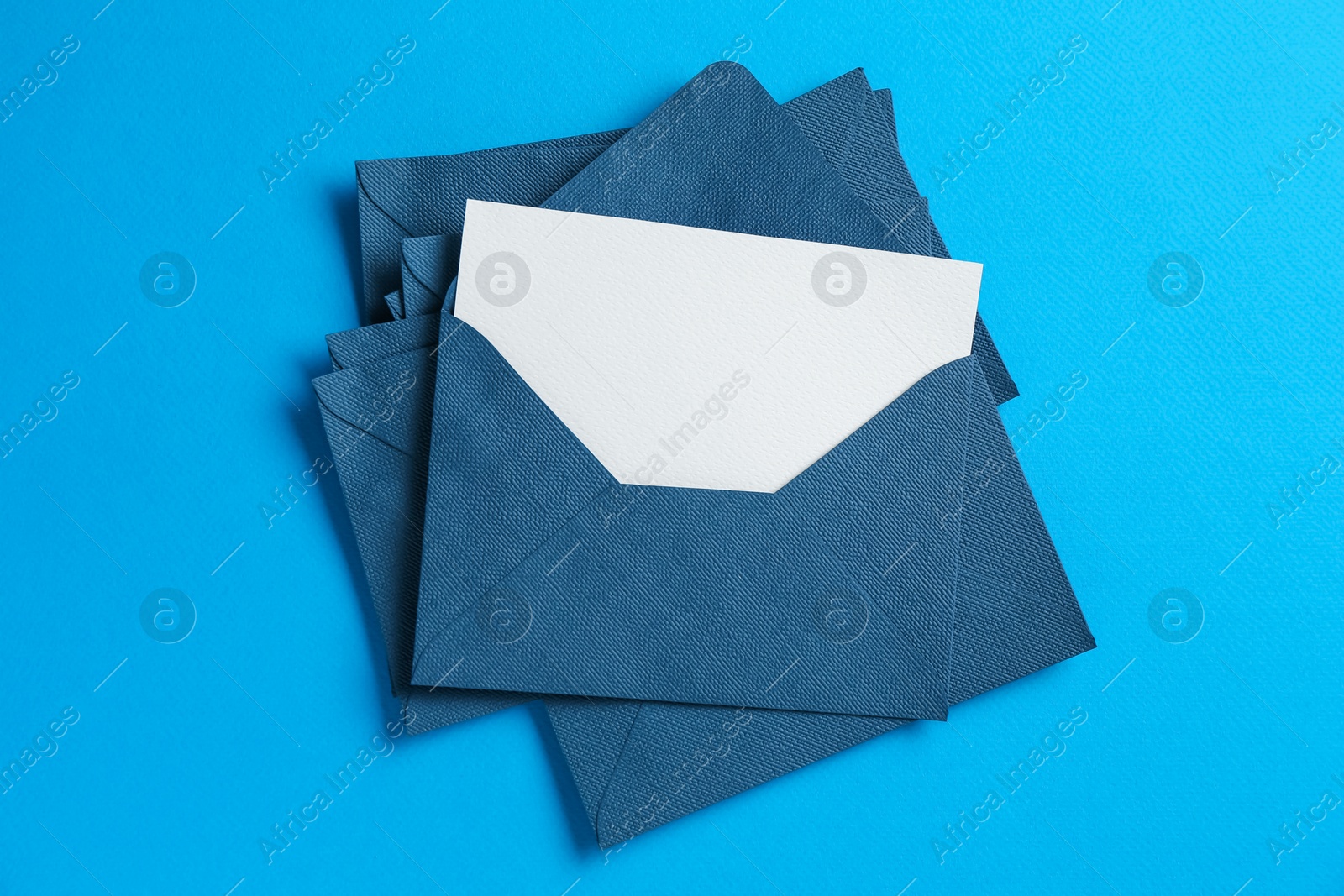 Blank invitation card and envelopes on light blue background, top view Photo of Blank invitation card and envelopes on light blue background, top view