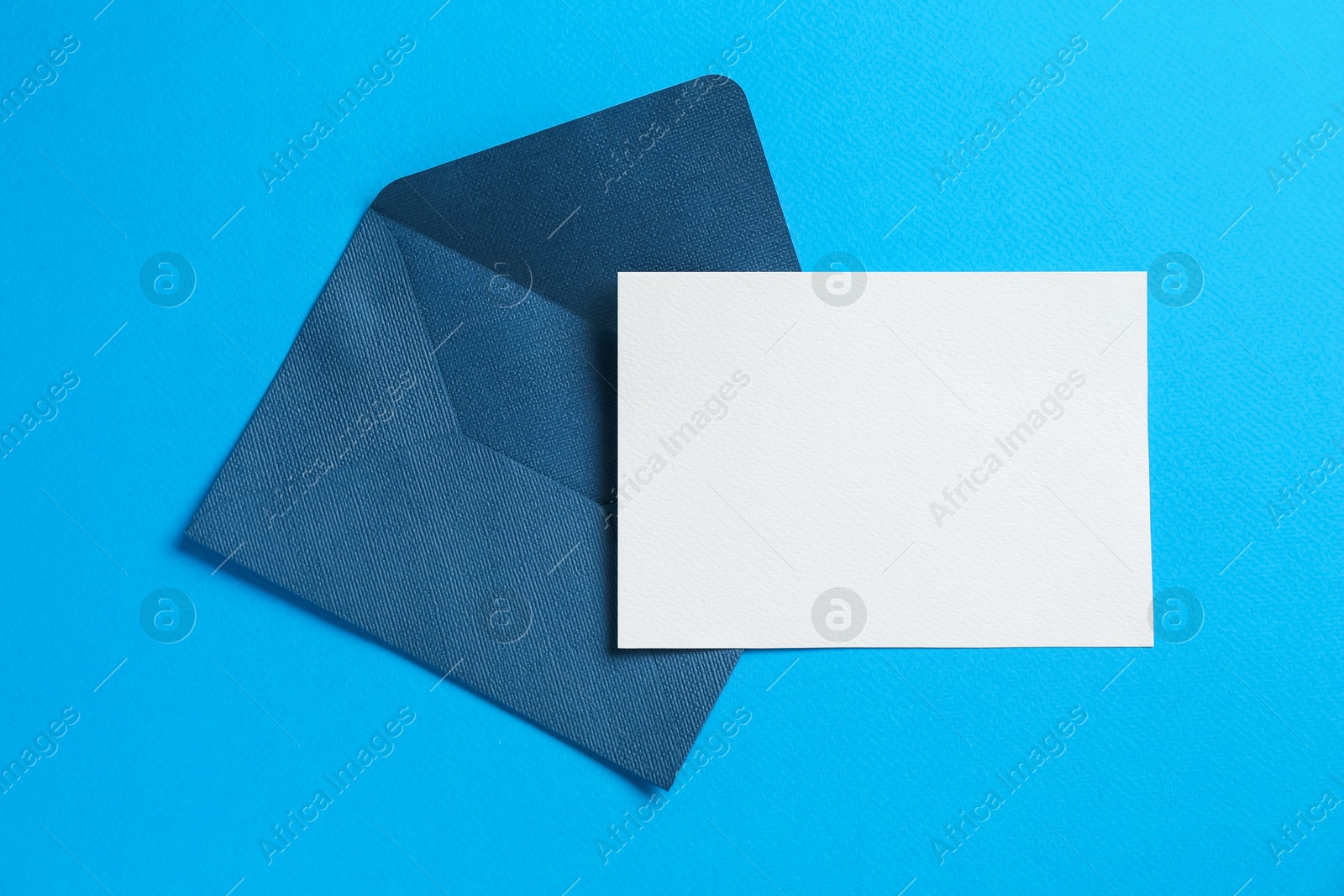 Blank invitation card and envelope on light blue background, top view. Space for design Photo of Blank invitation card and envelope on light blue background, top view. Space for design