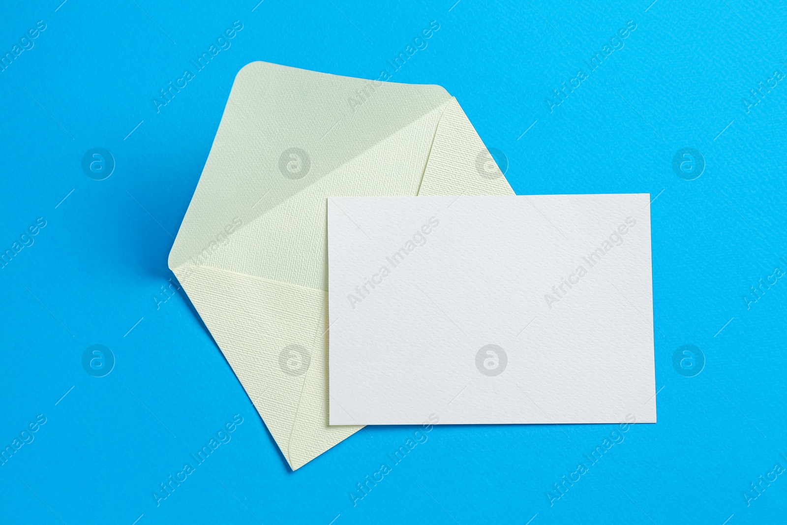Blank invitation card and envelope on light blue background, top view. Space for design Photo of Blank invitation card and envelope on light blue background, top view. Space for design