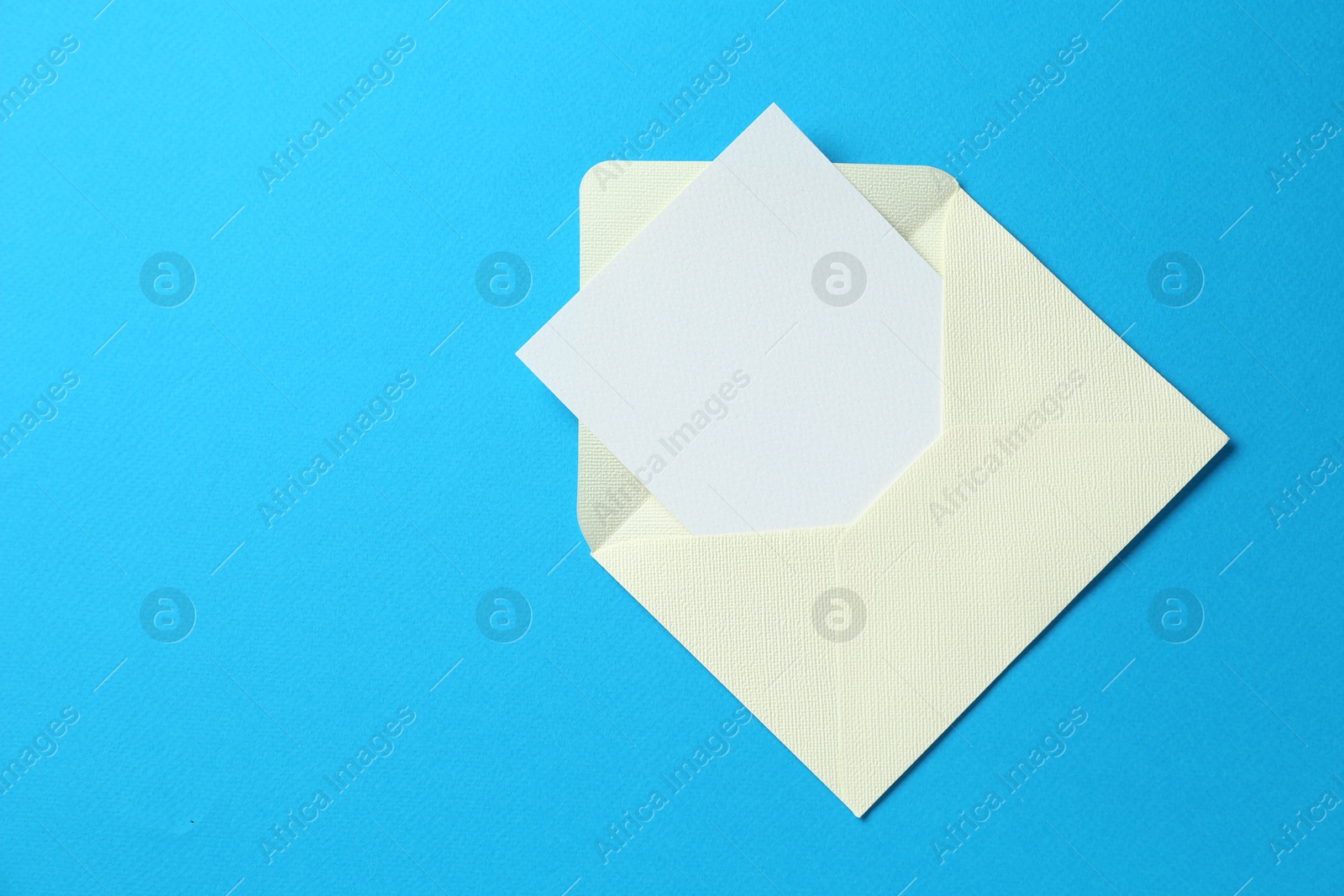 Blank invitation card and envelope on light blue background, top view. Space for text Photo of Blank invitation card and envelope on light blue background, top view. Space for text
