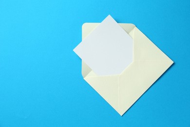 Photo of Blank invitation card and envelope on light blue background, top view. Space for text