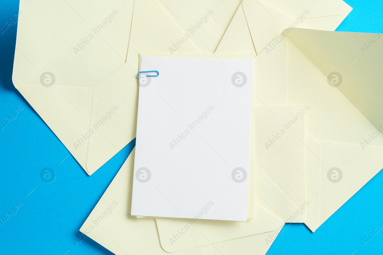Blank invitation card and envelopes on light blue background, flat lay. Space for design Photo of Blank invitation card and envelopes on light blue background, flat lay. Space for design