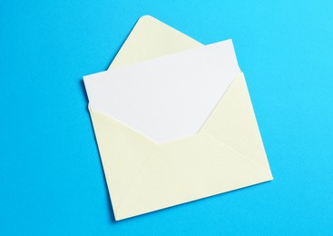 Photo of Blank invitation card and envelope on light blue background, top view. Space for design