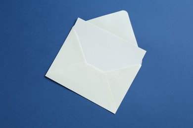 Photo of Blank invitation card and envelope on blue background, top view. Space for design