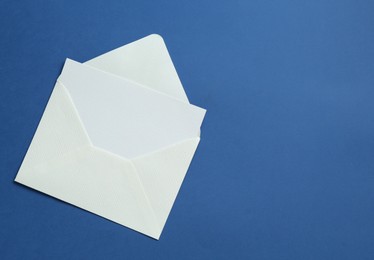 Photo of Blank invitation card and envelope on blue background, top view. Space for text