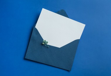 Photo of Blank invitation card and envelope on blue background, top view. Space for design