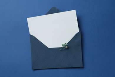 Photo of Blank invitation card and envelope on blue background, top view. Space for design