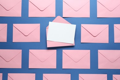 Photo of Blank invitation card and envelopes on blue background, flat lay. Space for design
