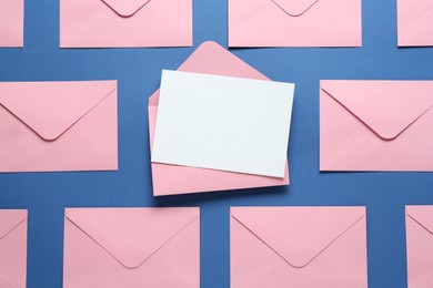 Photo of Blank invitation card and envelopes on blue background, flat lay. Space for design