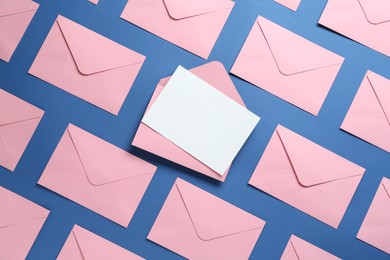 Photo of Blank invitation card and envelopes on blue background, flat lay. Space for design