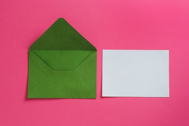 Photo of Blank invitation card and envelope on pink background, flat lay. Space for design