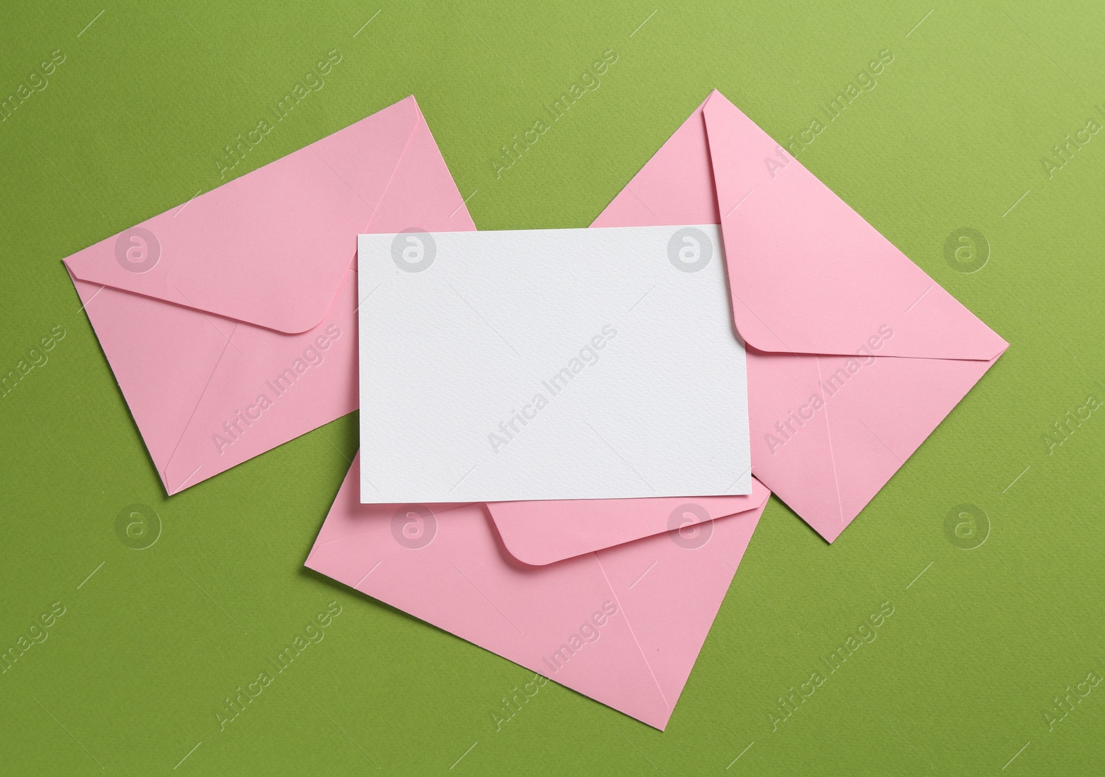 Blank invitation card and envelopes on green background, flat lay. Space for design Photo of Blank invitation card and envelopes on green background, flat lay. Space for design