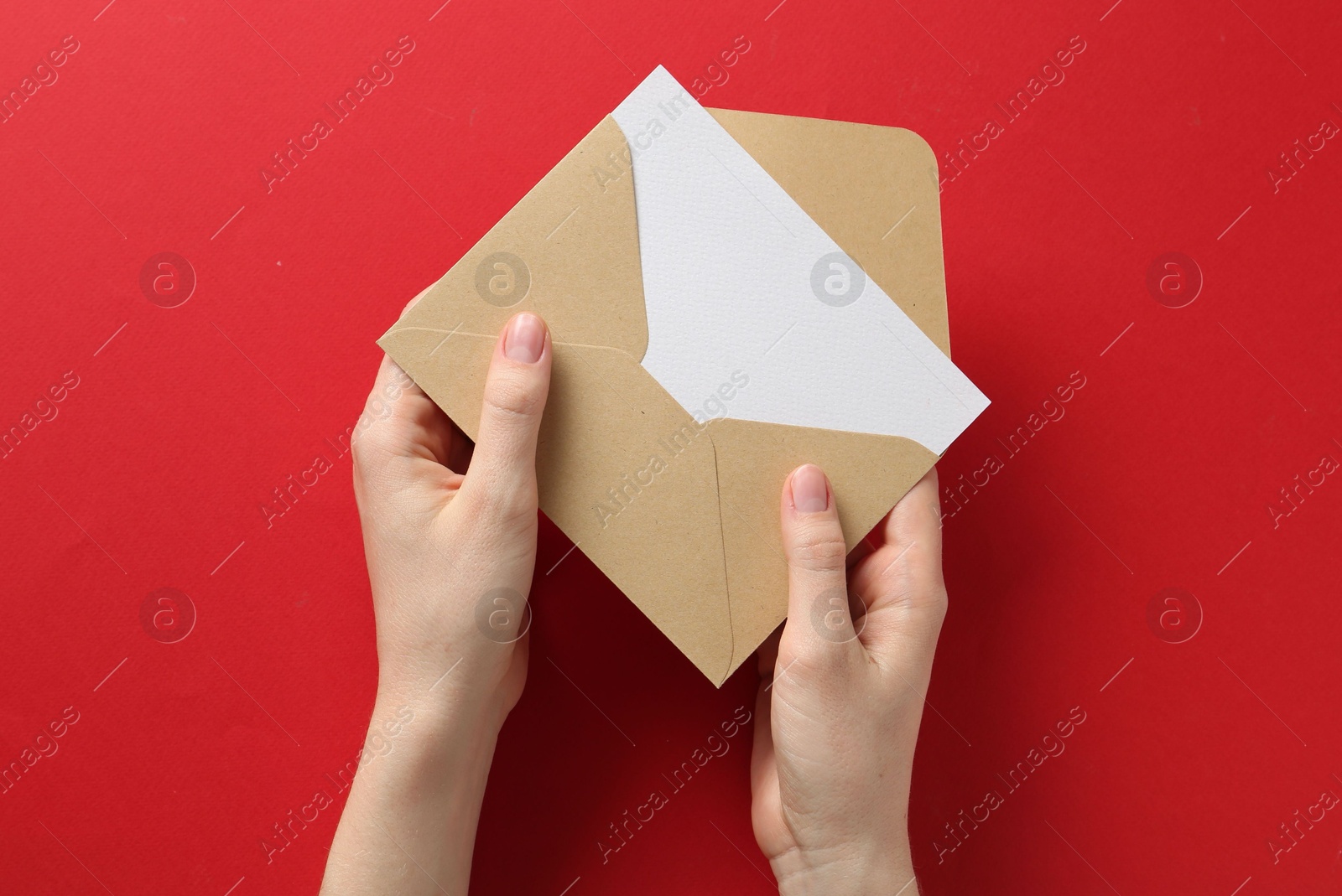 Woman holding envelope with blank invitation card on red background, top view Photo of Woman holding envelope with blank invitation card on red background, top view