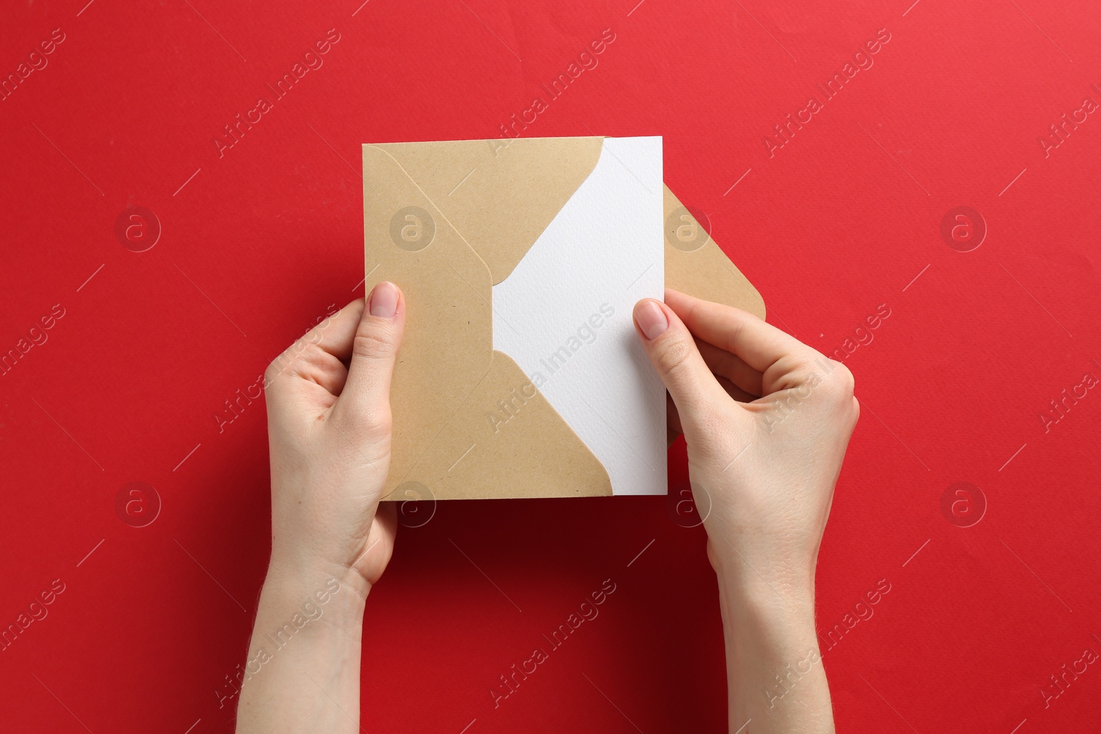 Woman holding envelope with blank invitation card on red background, top view Photo of Woman holding envelope with blank invitation card on red background, top view