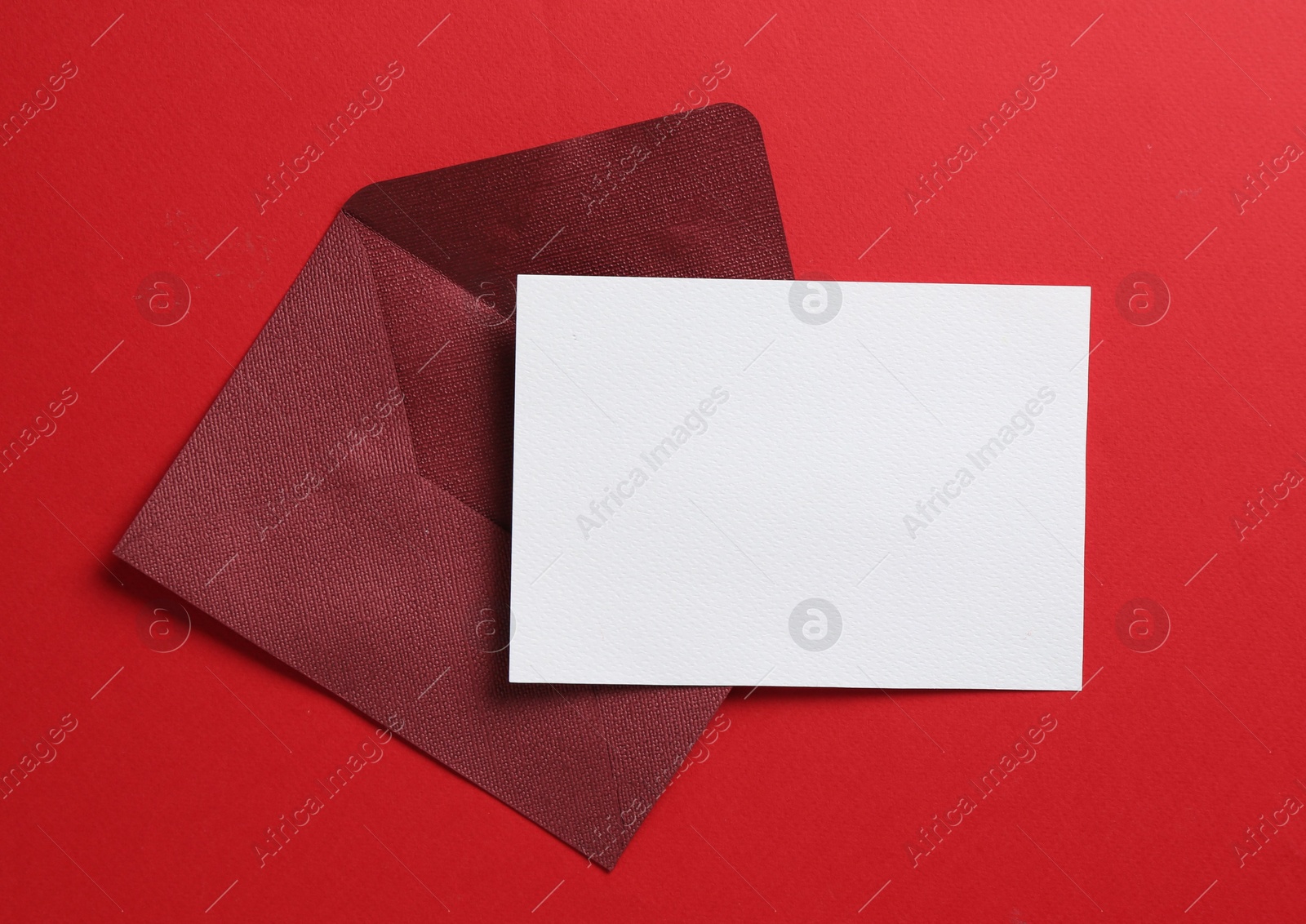 Blank invitation card and envelope on red background, top view. Space for design Photo of Blank invitation card and envelope on red background, top view. Space for design