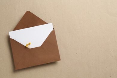 Photo of Blank invitation card with flowers and envelope on carton, top view. Space for text