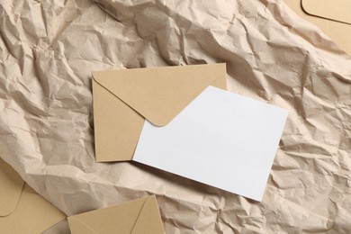 Photo of Blank invitation card and envelopes on parchment paper, flat lay. Space for design