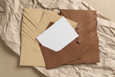Photo of Blank invitation card, envelopes and parchment paper on carton, top view. Space for design