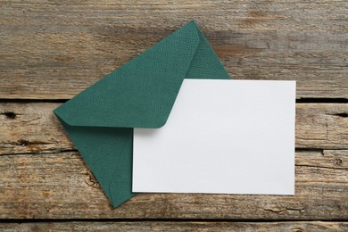 Photo of Blank invitation card and envelope on wooden table, top view. Space for design