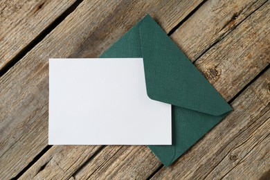 Photo of Blank invitation card and envelope on wooden table, top view. Space for design