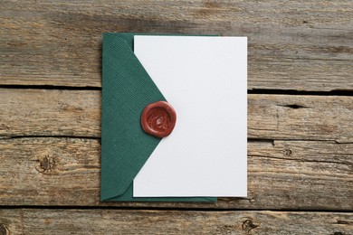Photo of Blank invitation card and envelope on wooden table, top view. Space for design