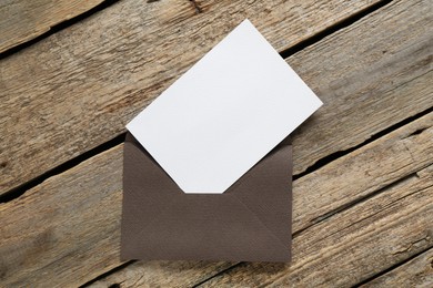 Photo of Blank invitation card and envelope on wooden table, top view. Space for design