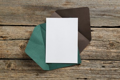 Photo of Blank invitation card and envelope on wooden table, top view. Space for design
