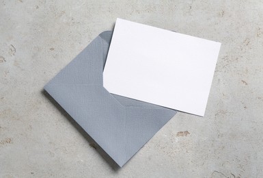 Photo of Blank invitation card and envelope on light grey table, top view. Space for design