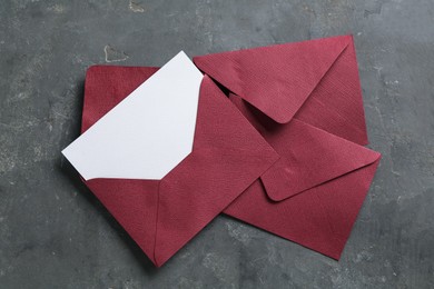 Photo of Blank invitation card and envelopes on grey table, flat lay