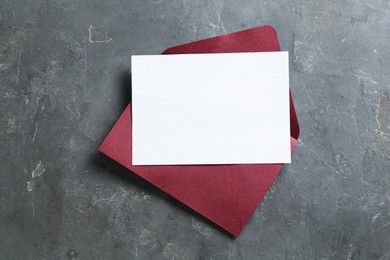 Photo of Blank invitation card and envelope on grey table, top view. Space for design
