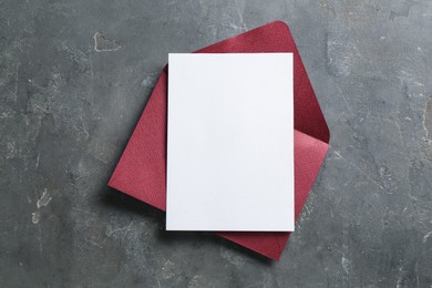 Photo of Blank invitation card and envelope on grey table, top view. Space for design