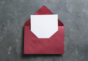 Photo of Blank invitation card and envelope on grey table, top view. Space for design