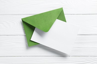 Photo of Blank invitation card and envelope on white wooden table, top view. Space for design