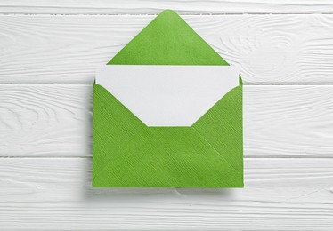 Photo of Blank invitation card and envelope on white wooden table, top view