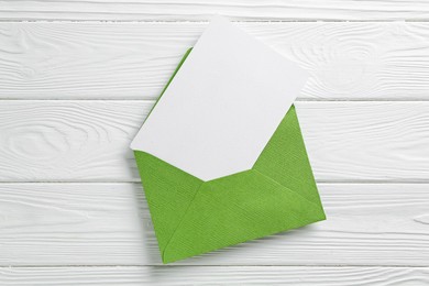 Photo of Blank invitation card and envelope on white wooden table, top view. Space for design