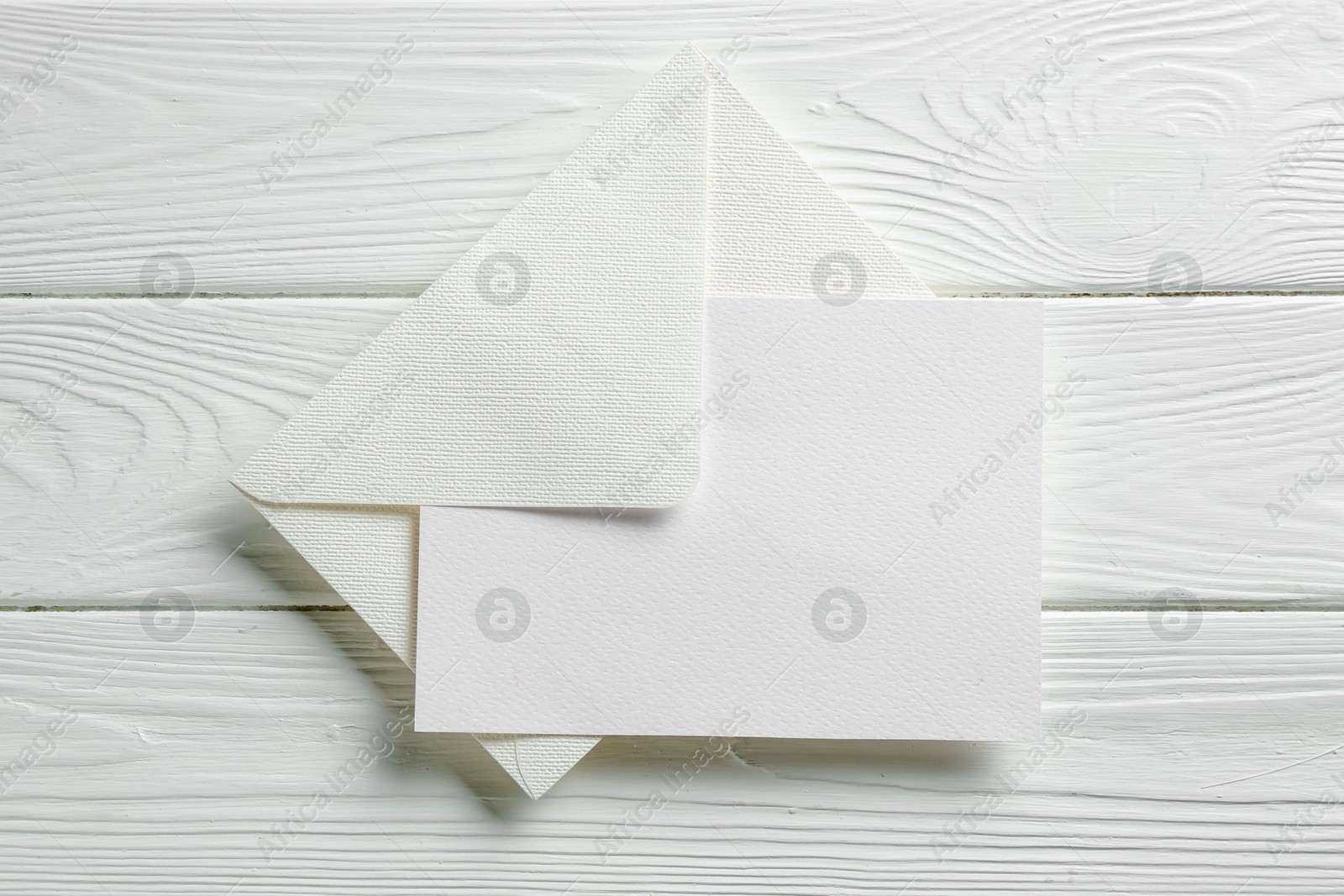 Blank invitation card and envelope on white wooden table, top view. Space for design Photo of Blank invitation card and envelope on white wooden table, top view. Space for design