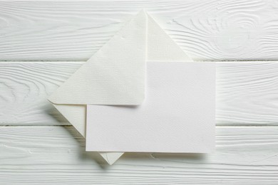 Photo of Blank invitation card and envelope on white wooden table, top view. Space for design