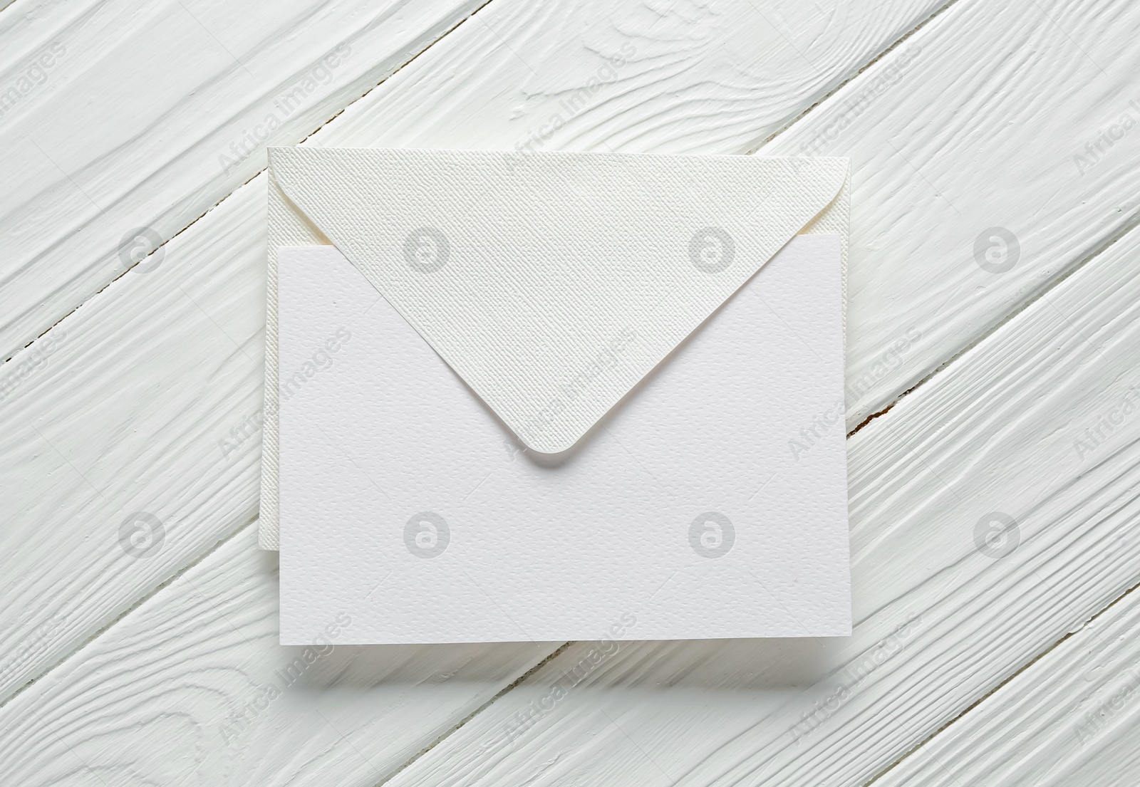 Blank invitation card and envelope on white wooden table, top view. Space for design Photo of Blank invitation card and envelope on white wooden table, top view. Space for design