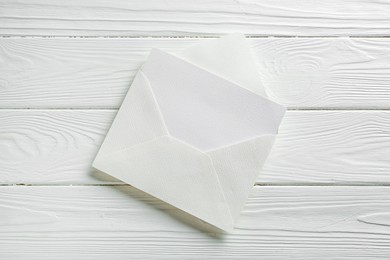 Photo of Blank invitation card and envelope on white wooden table, top view