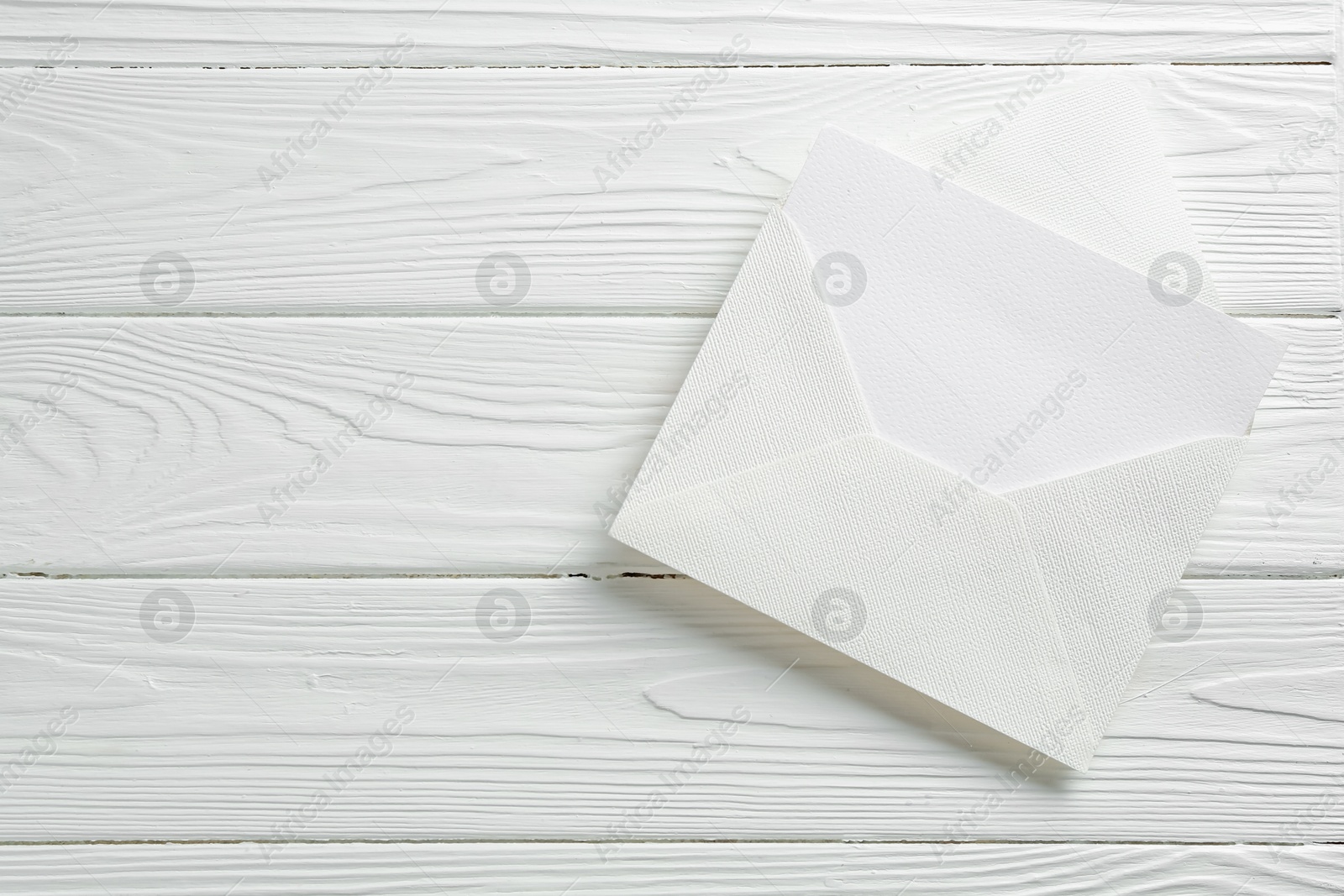Blank invitation card and envelope on white wooden table, top view. Space for text Photo of Blank invitation card and envelope on white wooden table, top view. Space for text