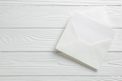 Photo of Blank invitation card and envelope on white wooden table, top view. Space for text