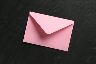 Photo of Beautiful invitation envelope on black table, top view