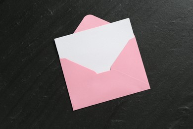 Photo of Blank invitation card and envelope on black table, top view. Space for design