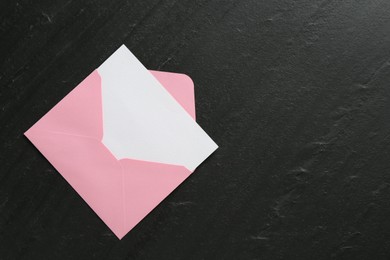 Photo of Blank invitation card and envelope on black table, top view. Space for text
