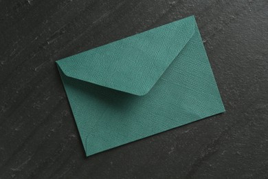 Photo of Beautiful invitation envelope on black table, top view