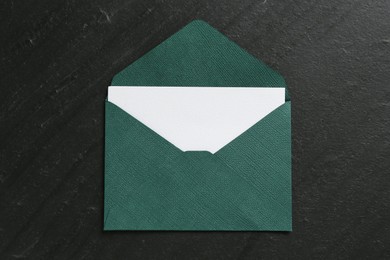 Photo of Blank invitation card and envelope on black table, top view