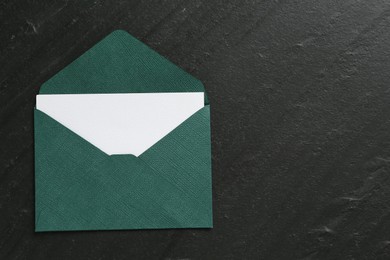 Photo of Blank invitation card and envelope on black table, top view. Space for text