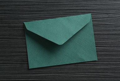 Photo of Beautiful invitation envelope on black textured table, top view