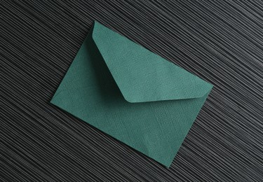 Photo of Beautiful invitation envelope on black textured table, top view