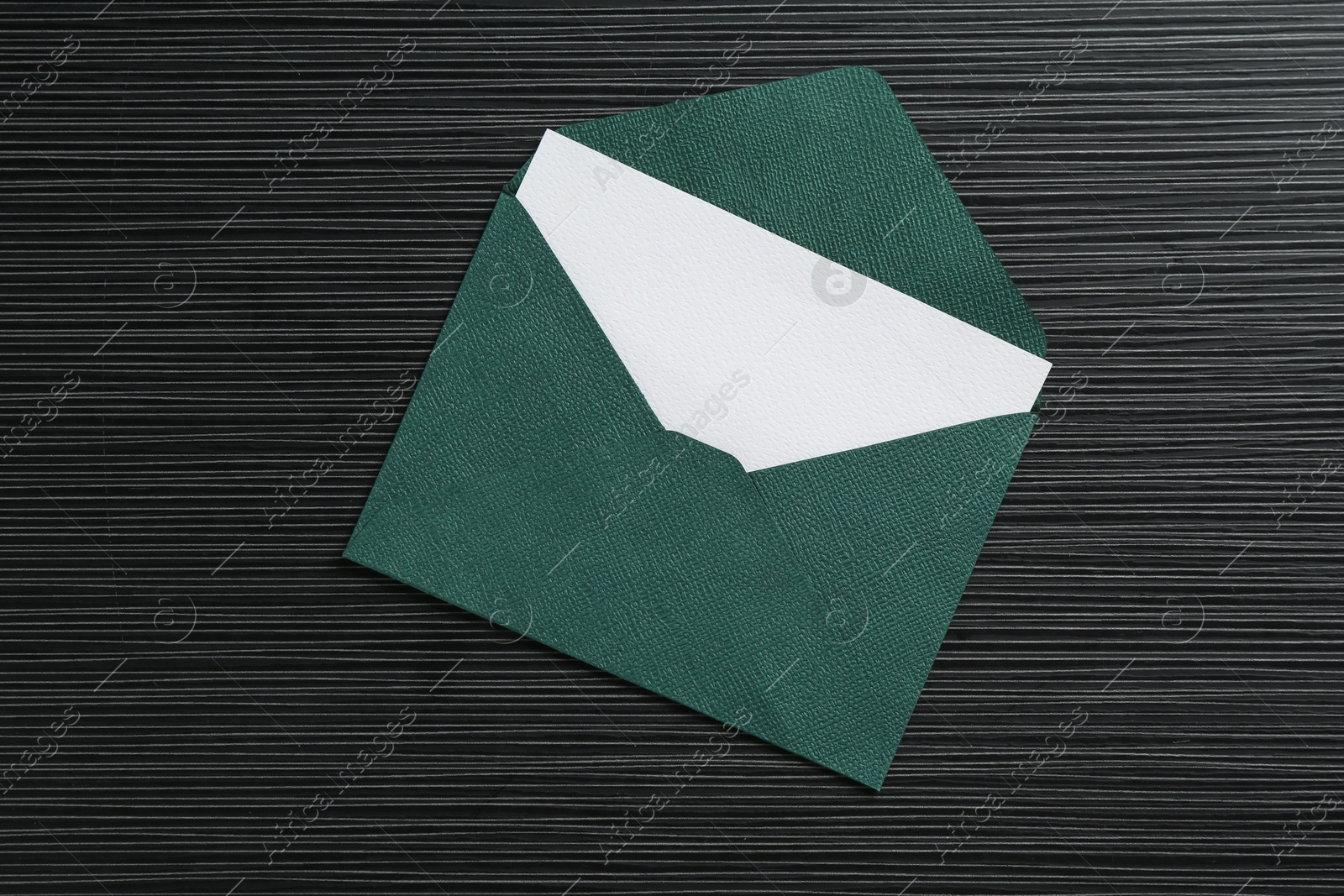 Blank invitation card and envelope on black textured table, top view Photo of Blank invitation card and envelope on black textured table, top view